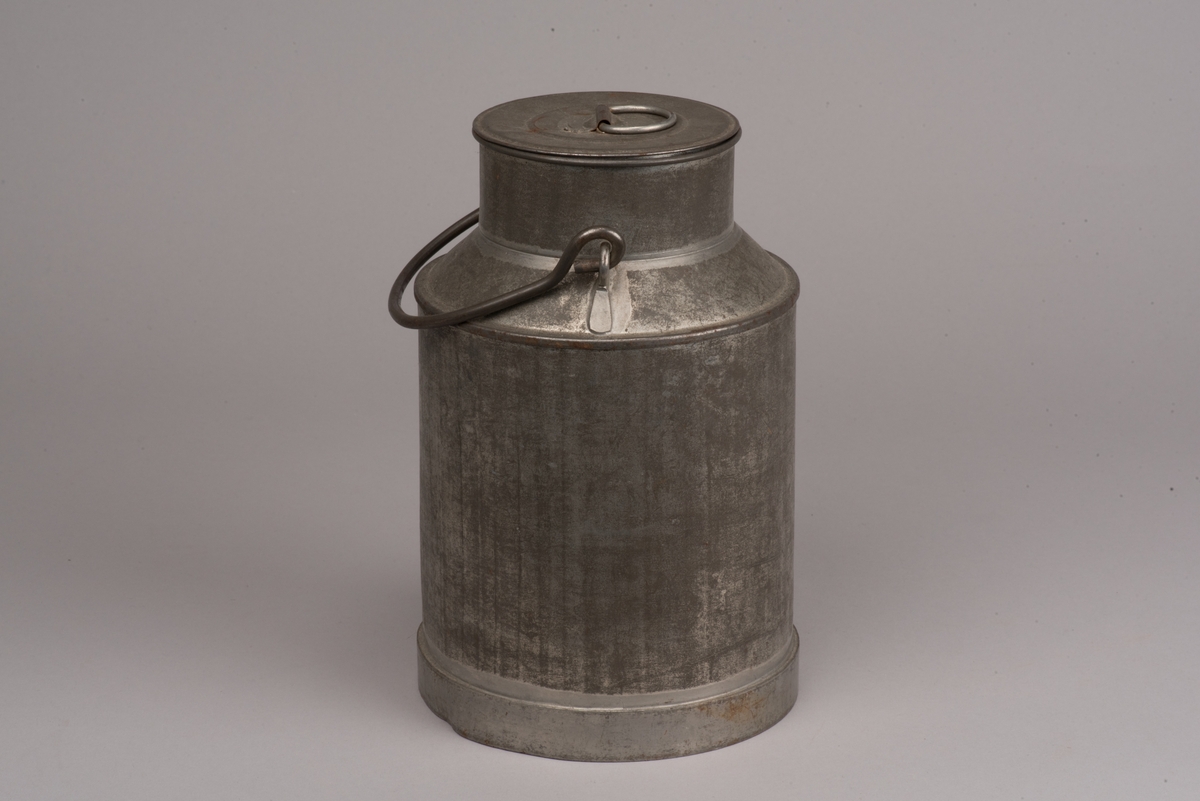 Cylindrisk mjölkanna med lock av bleckplåt.
Den avsmalnade halsen är försedd med ett bygelhandtag i stål. Även locket har ett pålött handtag.
