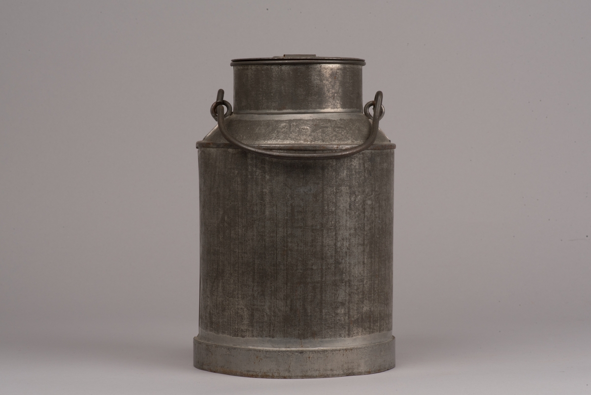 Cylindrisk mjölkanna med lock av bleckplåt.
Den avsmalnade halsen är försedd med ett bygelhandtag i stål. Även locket har ett pålött handtag.