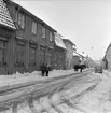 Parti av Follinegatan i Skänninge den snörika vintern 1959 där ett snart utdaterat ekipage möter ett något mindre ålderdomligt i form av en Ford Escort.