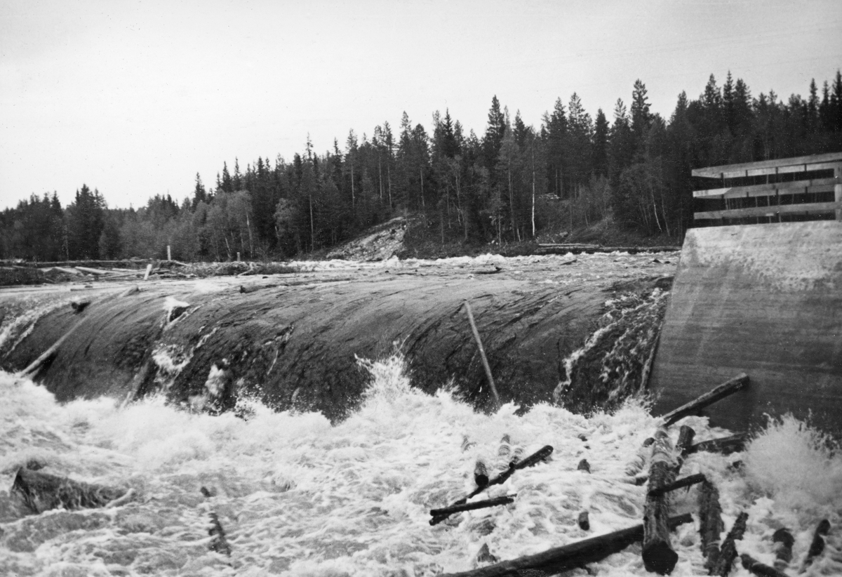 Tømmerfløting i elva Søndre Osa i Åmot kommune i Hedmark. Fotografiet er tatt våren 1936, ved den da nybygde kraftverksdammen ved Kvernfallet. I forgrunnen ser vi hvordan vannet og tømmerstokkene fløt over den avrundete damkrona. Den underliggende konstruksjonen, som vi ikke ser på dette bildet, var utført i armert betong. Bildeter tatt fra søndre elvebredd, skrått mot dammen. 

I 1936 var det innmeldt 383 088 tømmerstokker til fløting fra Osensjøen og tilflytende vassdrag. 28 prosent av stokkene ble levert ved Slemma, 10 prosent ved Nordre Osa, 7 prosent ved Brøa, 13 prosent ved Ena med Ulvsjøvassdraget, 7 prosent ved Tverrena og resten, 35 prosent, ble levert ved Osensjøens strender. Alt dette tømmeret. pluss noe av et kvantum på 72 506 stokker som var levert ved Søndre Osa, skulle passere den nye kraftverksdammen ved Kvernfallet. Aktørene i fløtinga var naturlig nok spente på om dammen kom til å bli et hinder der stokkene satte seg fast på eller like nedenfor dammen. Det skjedde ikke. Kvernfalldammen kom ikke til å skape nevneverdige problemer for tømmerfløtinga.