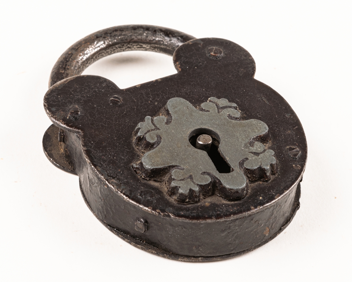 Hänglås, av järn, med nyckelhålet omgivet av skiva med bladornament vid kanterna.