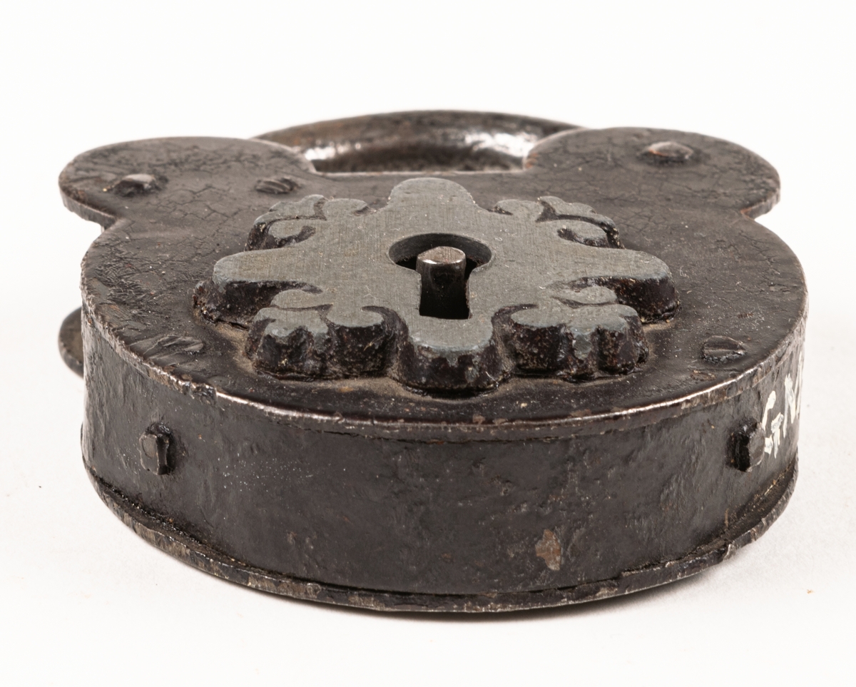 Hänglås, av järn, med nyckelhålet omgivet av skiva med bladornament vid kanterna.