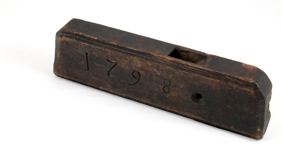 Profilhøvel: Oversiden rett, trapesformet hull for høveltann. Skrå vegger ned til åpning under som er buet i       -form. Hullet for høveltann åpent mot en side, profilert i -form. Den motsatte side rett med inskripsjon: "1798". Sirkulært hull tvers gjennom.