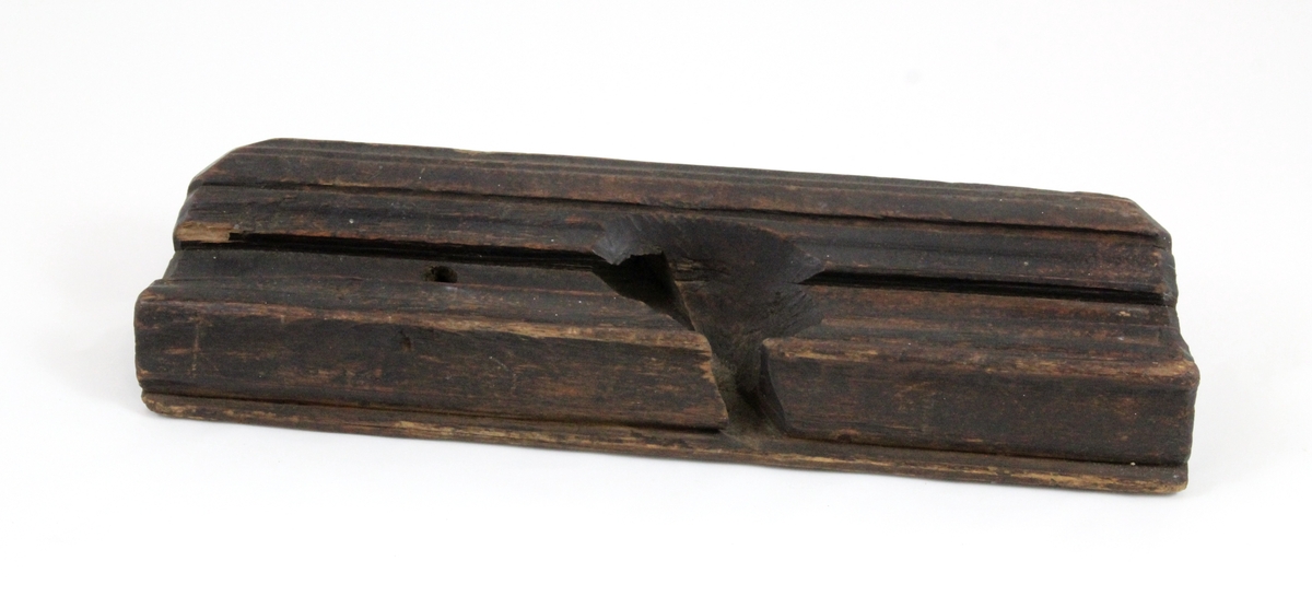 Profilhøvel: Oversiden rett, trapesformet hull for høveltann. Skrå vegger ned til åpning under som er buet i       -form. Hullet for høveltann åpent mot en side, profilert i -form. Den motsatte side rett med inskripsjon: "1798". Sirkulært hull tvers gjennom.