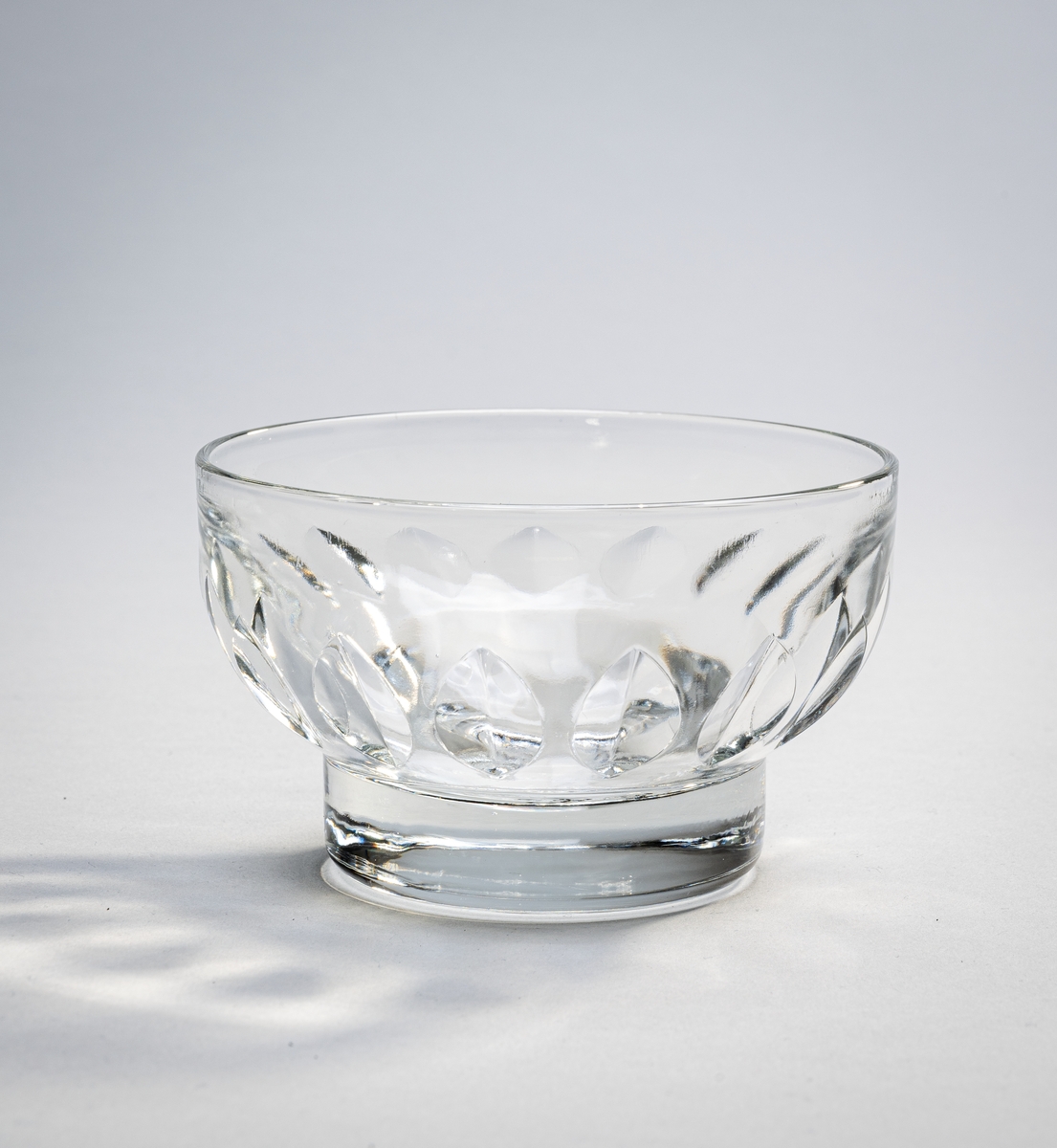 To identiske glasskåler fra NFDS (Nordenfjeldske Dampskibsselskap). De er av klart glass. Nede er det en 1,5cm høy stett i massivt glass. På skålen er det mandelsformet dekor (dekor som går inn i glasset).