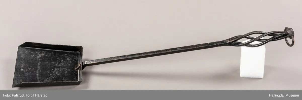 En pesspade eller askespade i smijern med vridd håndtak med ring i enden.