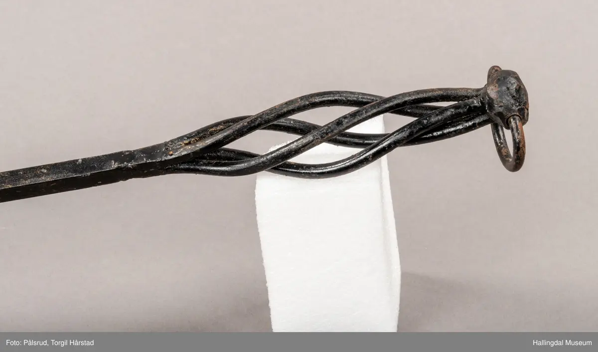 En pesspade eller askespade i smijern med vridd håndtak med ring i enden.