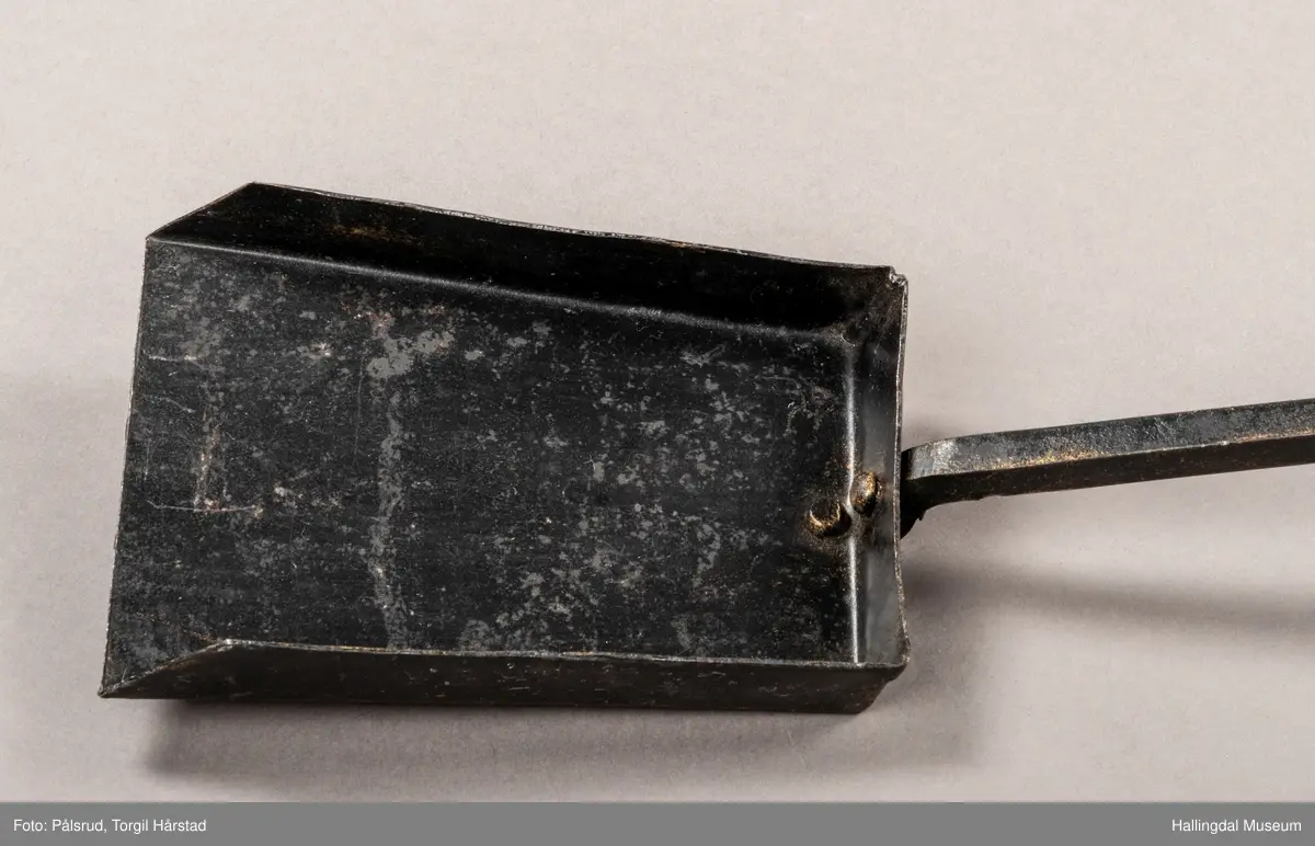 En pesspade eller askespade i smijern med vridd håndtak med ring i enden.