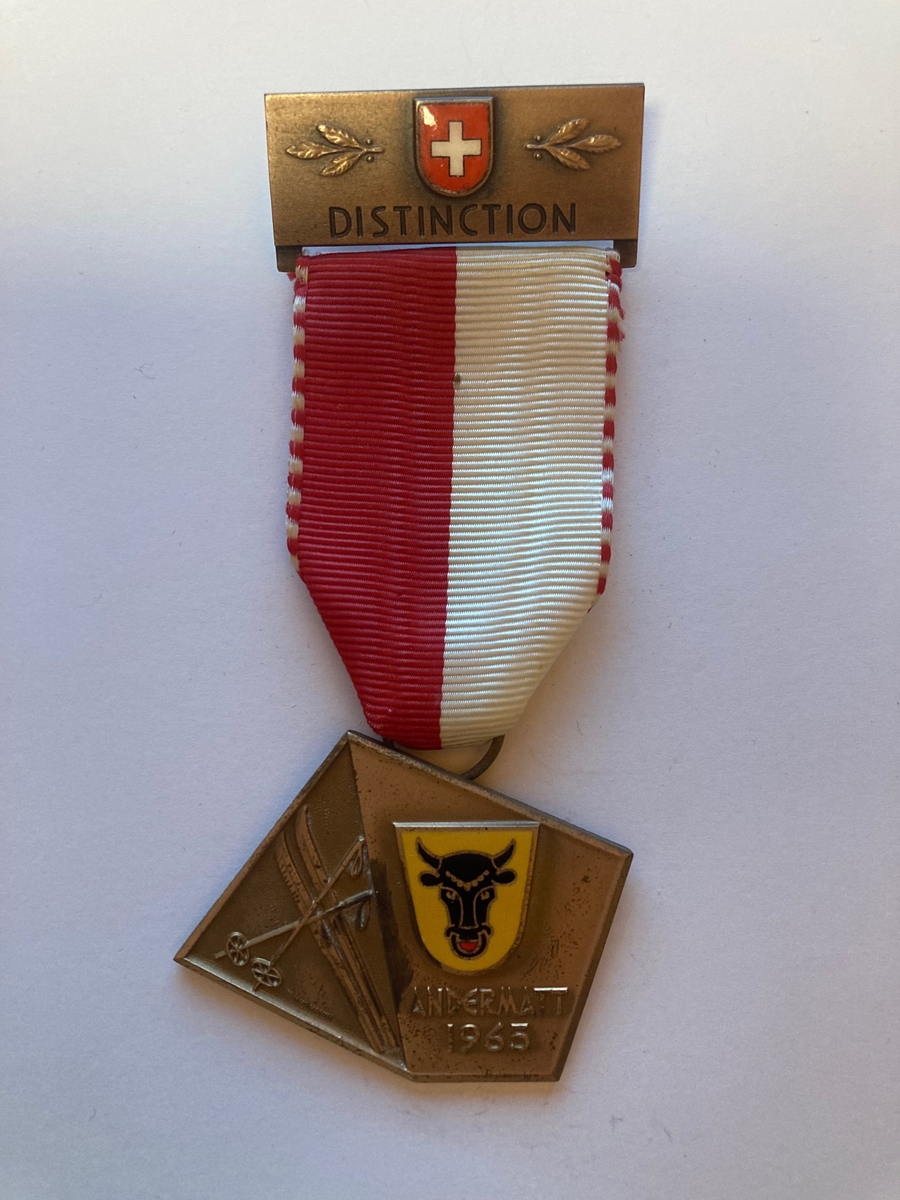 Forsiden av medaljen består av ett par ski med staver til venstre. På høyre side er det avbildet våpenet til kantonen Uri i Sveits med "Andermatt 1965" skrevet under. Våpenet er gult med et oksehode i midten. 