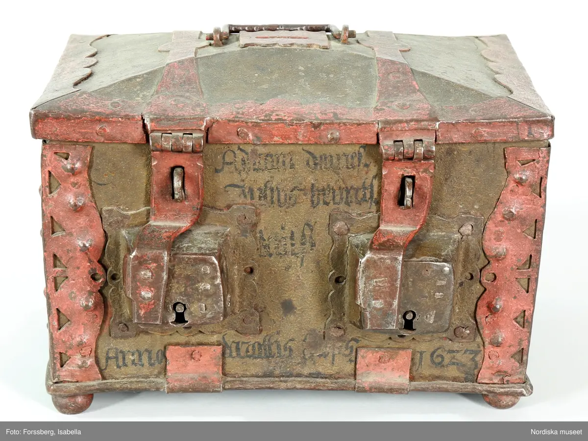 Huvudliggaren;
"a-c, Skrin, som tillh. hovslagarämbetet i Stockholm, dat. 1623. Av järnplåt m. rödmålade beslag och 2 nycklar; rekt. med fällock. fr. hovslagarämbetet i Stockholm 1868. 
a) skrin, b) nyckel (L 9 cm), c) nyckel (L 7,8 cm). 
Från Statens historiska museum 1925.

Inventering Sesam 1997-1998:
B 31, Djup 23, H 23 cm
Skrin (a), rektangulärt, med kupigt fällock, av järnplåt. Järnband fästade runt botten. Järnplåtarna ihopsatta med nitar på gavlarna.
Beslag med utstansad dekor runt hörnen.
Fasat lock med beslag runt kanterna, två bandgångjärn fästade på utsidan samt med gångjärn även vid framkanten där två låshaspar sitter.
Två utanpåliggande lås på framsidan, låses med låshasparna samt nycklar som nu saknas (har antagligen varit märkta b och c).
Skåra mitt på locket, att lägga mynt i, läderbit fästad runt öppningen på insidan, beslag på ovansidan.
Bygelhandtag fästat i märlor på locket.
Utvändigt målat i brunaktig färg, otydlig inskrift i svart på framsidan samt årtalet " 1623 ", beslagen målade i rött. Skrinet står på kulfötter, med rester av röd färg.
Från Hovslagarämbetet i Stockholm 1862.
Agnetha Blomberg 1998