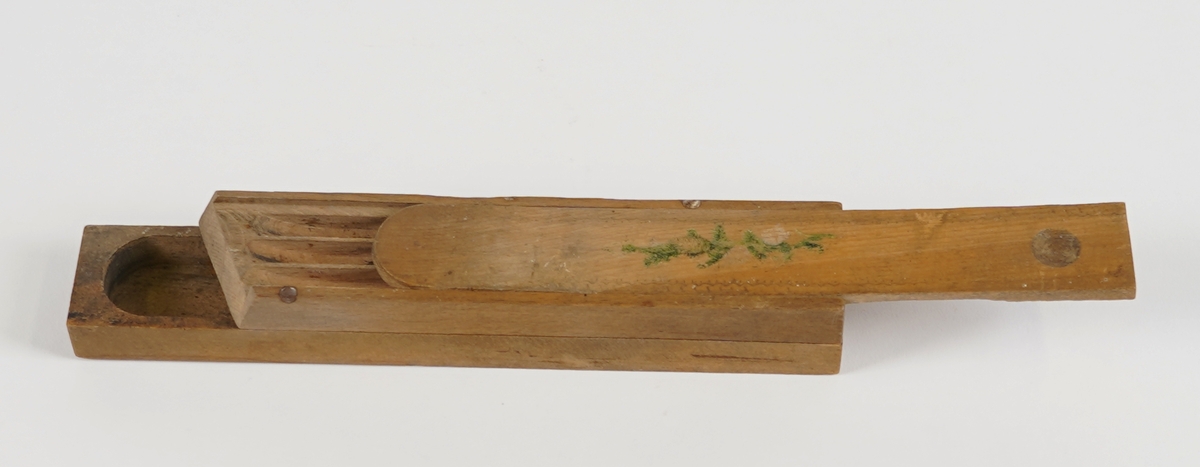 Pennal med to rom. Det nedste rommet vert tilgjengeleg ved å svinge det øvste til sides, og er avslutta i boge i eine enden. Det øvste rommet har skyvelok, er delt i tre smale rom, og er avslutta med ein skrå ende. Skyveloket er avrunda i eine enden, og i den andre er det ei halvkuleforma fordjuping som gjer det lettare å skyve loket fram og attende. Loket har bølgeforma dekor rundt kanten, samt eit granbar-motiv midt på.