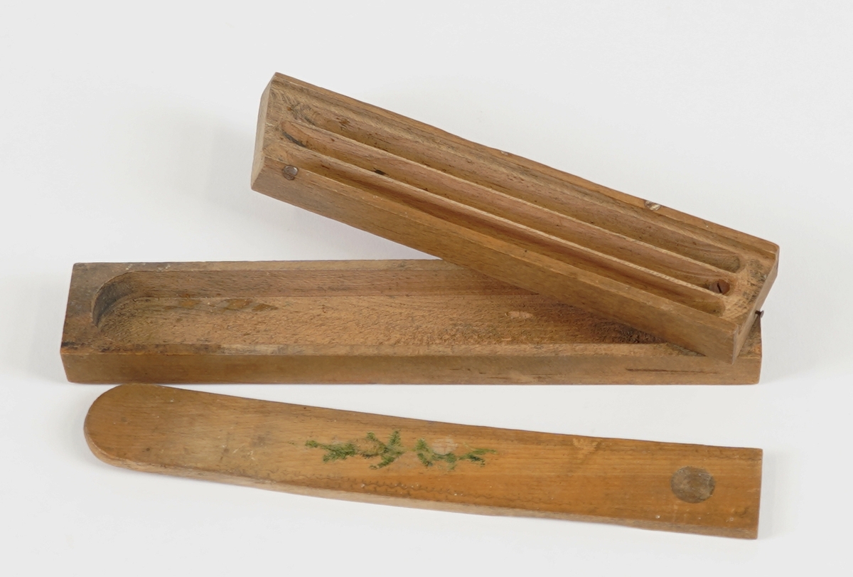 Pennal med to rom. Det nedste rommet vert tilgjengeleg ved å svinge det øvste til sides, og er avslutta i boge i eine enden. Det øvste rommet har skyvelok, er delt i tre smale rom, og er avslutta med ein skrå ende. Skyveloket er avrunda i eine enden, og i den andre er det ei halvkuleforma fordjuping som gjer det lettare å skyve loket fram og attende. Loket har bølgeforma dekor rundt kanten, samt eit granbar-motiv midt på.