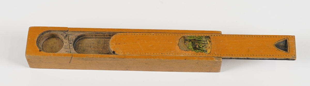 Penal med to rom. Det nedste rommet vert tilgjengeleg ved å svinge det øvste til sides. Det øvste rommet har skyvelok, og er delt i to rom. Skyveloket er avrunda i eine enden, og i den andre er det ei fordjuping som gjer det lettare å skyve loket fram og attende. Loket har stipla dekor rundt kanten, samt teikning av ein bukk midt på. I det nedste rommet ligg det to penneskaft, utan spissar. På innsida av loket er det set merke for kvar halve cm på eine langsida.