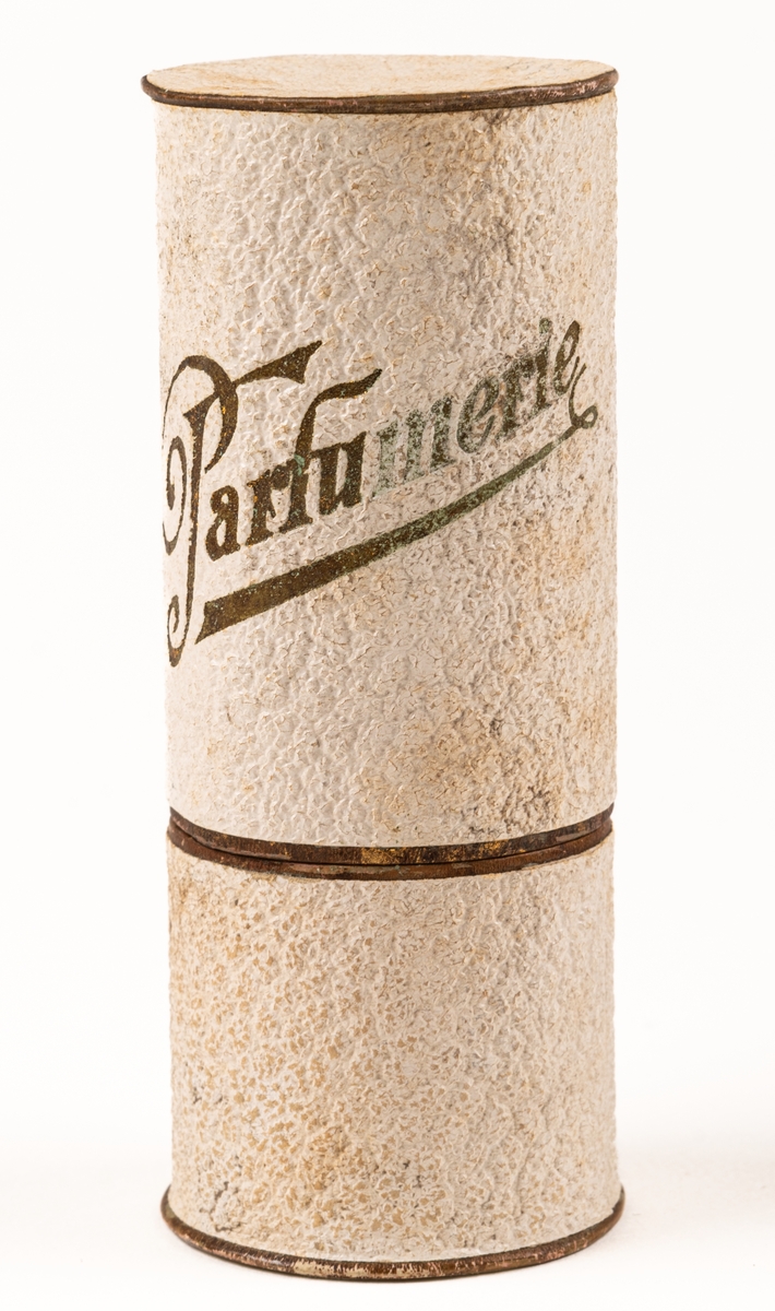 Parfymask i papp, cylinderformad, i glansigt vitt papper med guldfärgad text "Parfumerie".