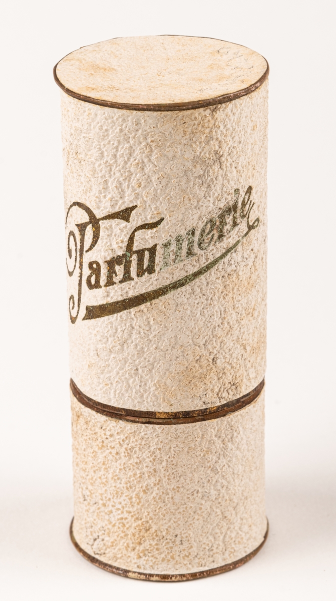 Parfymask i papp, cylinderformad, i glansigt vitt papper med guldfärgad text "Parfumerie".