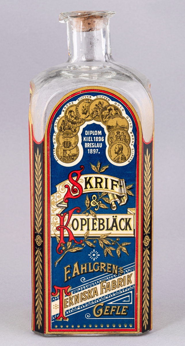 Glasflaska med kork innehållande bläck. Flaskan fyrsidig. Etikett med text "Skrif- & Kopiebläck" på framsidan.