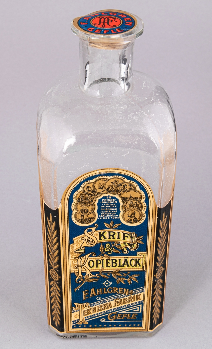 Glasflaska för bläck, fyrkantig med kork. Etikett på tre sidor, "Skrif- & Kopiebläck", "F. Ahlgrens Tekniska Fabrik Gefle".
