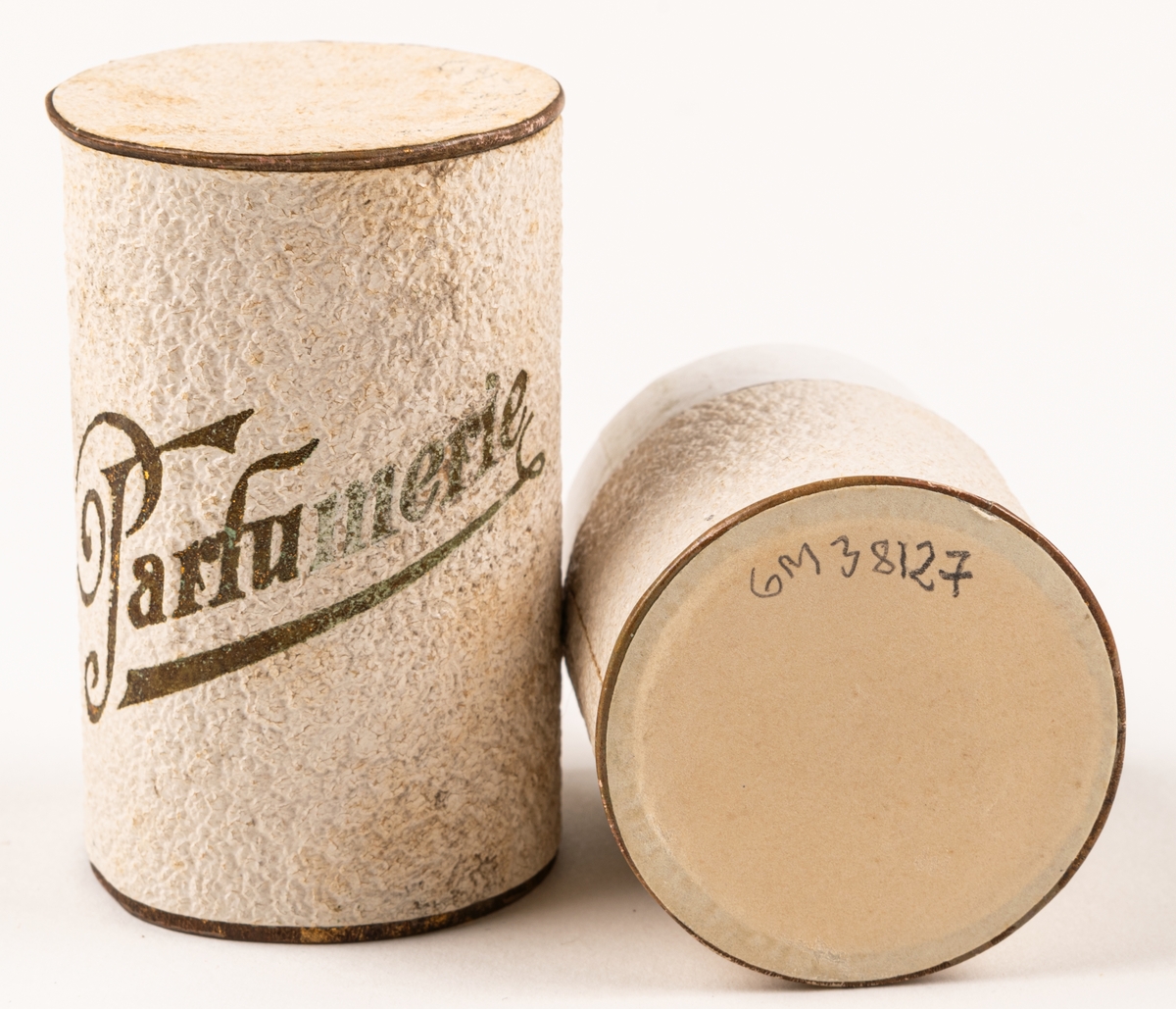 Parfymask i papp, cylinderformad, i glansigt vitt papper med guldfärgad text "Parfumerie".