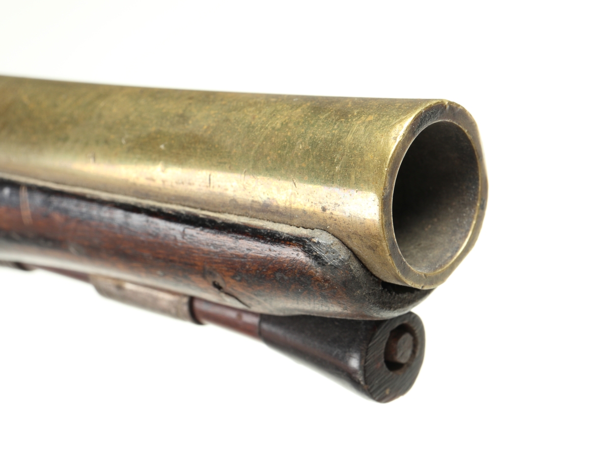 Flintlåspistol med helstock och lås i stål i s.k. Centuckystil. Pipan är gjord i mässing, och kolvkappa, varbygel, sidobleck, tumplåt och rörkor i silver. Pipan är märkt "ST-965", samt två kontrollstämplar från London, och som är åttakantig i formen, men övergår i cylindrisk form ut mot mynningen. Kolvkappan har silverstämplar från Birmingham, varbygeln likaså. Sidoblecket är utformat som blomsterslingor, och kolvkappan som en maskaron. Varbygeln är ornamenterad med en blomma i en oval. Längst fram är den utformad som ett ekollon. Tumplåten är märkt med "EC". Laddstock finns under framstocken.
Inskrivet i huvudkatalogen 1974.