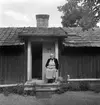 Cedersberg under Snäsätter i Västra Harg. På trappan sitter sannolikt stugans sista fast boende, Elin Augusta Karlsson. Året är 1949 och hon har varit änka sedan sommaren 1946.