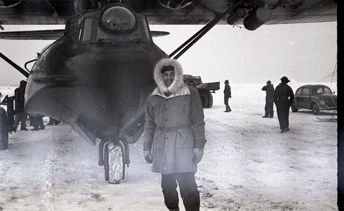 Transportformann Torleif Pedersen foran en av de to Catalinaene som landet 11.mars 1958 på den nylig opparbeidede flystripa i Adventdalen. Dette var de første postflyene som landet i Longyearbyen. Fra slutten av 40-tallet hadde Catalinaer droppet postsekker på Svalbard om våren. Denne flystripa ble opparbeidet i februar 1958 for at en Catalina skulle kunne lande for å hente en alvorlig syk person. Ambulanseflyet landet 9.februar, og returnerte samme dag. Dette satte i gang en aksjon for at postfly også skulle lande vinterstid, sånn at man også kunne sende post ned med det. Se s.11 i Svalbardposten nr.17 fra 14.mars 1958.