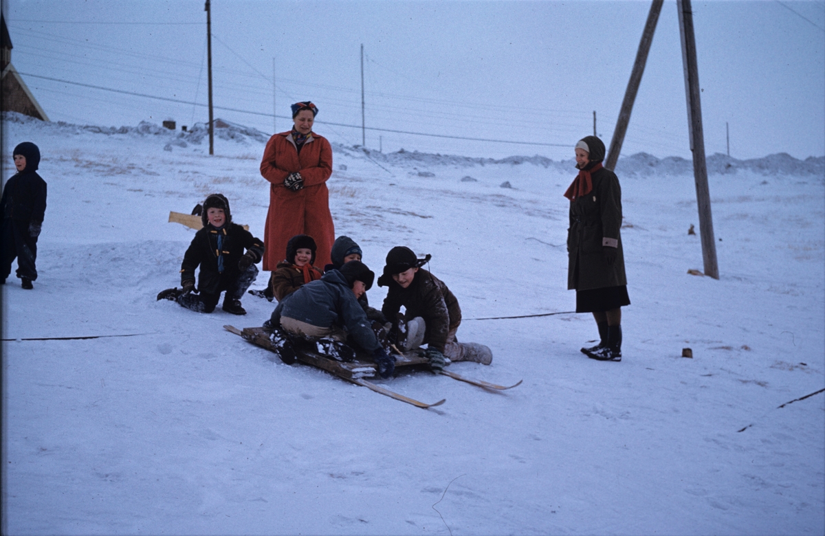 Vinter i Longyearbyen. Barn som aker. Fra venstre: ukjent, Kurt Helgesen, Randi Nødtvedt, Wilhelm Gjevestad og Kurt Skog. Til høyre Ranveig Nødtvedt