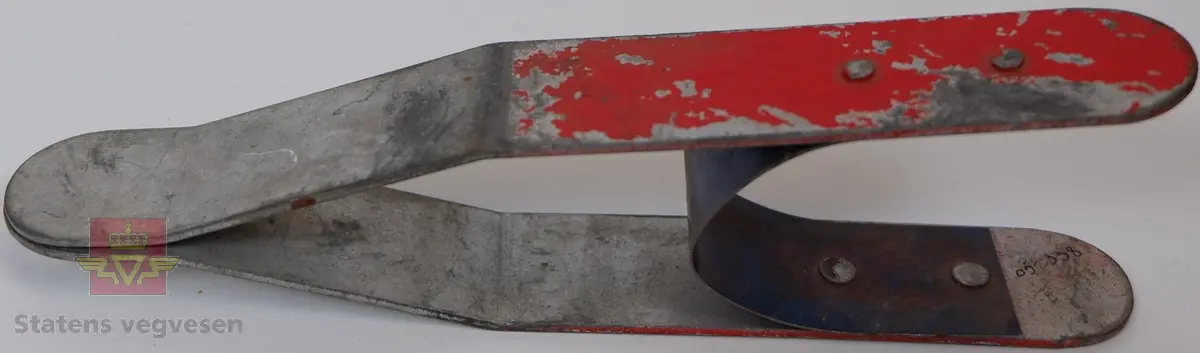 Grå lerret pose med blå påskrift. Posen inneholder 22 fjærende klyper av galvanisert metall. Rødmalte felt på begge sider.