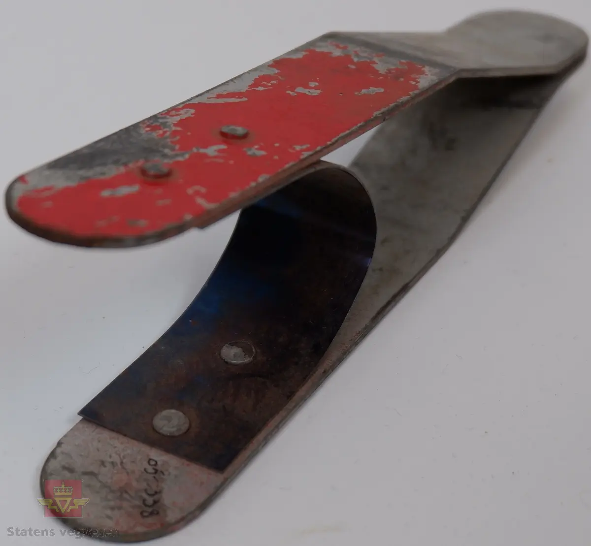 Grå lerret pose med blå påskrift. Posen inneholder 22 fjærende klyper av galvanisert metall. Rødmalte felt på begge sider.
