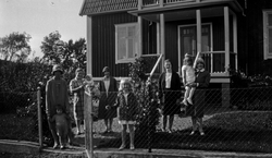 Fem vuxna och fyra barn samlade framför ett hus.