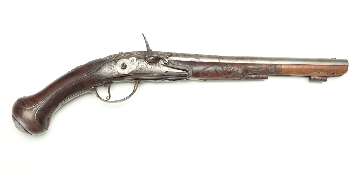 Flintlåspistol med helstock i valnöt. Pipan, varbygeln, tumplåten och sidoplåten är i ciselerad stål med upphöjda ornament. På låsblecket är namnet Willem van Essen graverat. Även framstocken har utsirade ornament i relief. Här finns även en spetsrörka och en överrörka, även dessa i stål. Kolvkappan, i stål, är försedd med en kolvknapp iform av en maskaron, omgärdad av ett slingmönster. Pipan är slätborrad, och här finns ett litet mässingskorn längst ut vid mynningen.
Inskrivet i huvudkatalogen 1869.