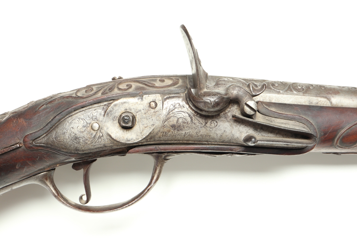 Flintlåspistol med helstock i valnöt. Pipan, varbygeln, tumplåten och sidoplåten är i ciselerad stål med upphöjda ornament. På låsblecket är namnet Willem van Essen graverat. Även framstocken har utsirade ornament i relief. Här finns även en spetsrörka och en överrörka, även dessa i stål. Kolvkappan, i stål, är försedd med en kolvknapp iform av en maskaron, omgärdad av ett slingmönster. Pipan är slätborrad, och här finns ett litet mässingskorn längst ut vid mynningen.
Inskrivet i huvudkatalogen 1869.