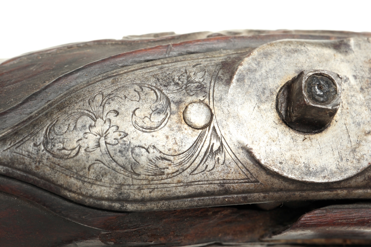 Flintlåspistol med helstock i valnöt. Pipan, varbygeln, tumplåten och sidoplåten är i ciselerad stål med upphöjda ornament. På låsblecket är namnet Willem van Essen graverat. Även framstocken har utsirade ornament i relief. Här finns även en spetsrörka och en överrörka, även dessa i stål. Kolvkappan, i stål, är försedd med en kolvknapp iform av en maskaron, omgärdad av ett slingmönster. Pipan är slätborrad, och här finns ett litet mässingskorn längst ut vid mynningen.
Inskrivet i huvudkatalogen 1869.