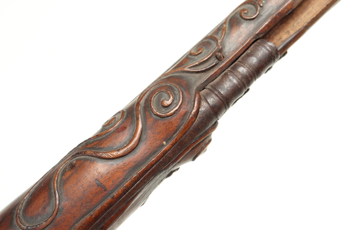 Flintlåspistol med helstock i valnöt. Pipan, varbygeln, tumplåten och sidoplåten är i ciselerad stål med upphöjda ornament. På låsblecket är namnet Willem van Essen graverat. Även framstocken har utsirade ornament i relief. Här finns även en spetsrörka och en överrörka, även dessa i stål. Kolvkappan, i stål, är försedd med en kolvknapp iform av en maskaron, omgärdad av ett slingmönster. Pipan är slätborrad, och här finns ett litet mässingskorn längst ut vid mynningen.
Inskrivet i huvudkatalogen 1869.