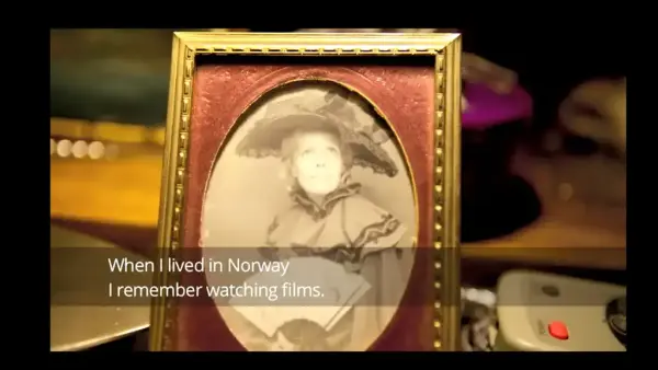 Between coasts - Gammelt foto av kvinne mes stor hatt, vifte og rysjekjole i gammel billedramme