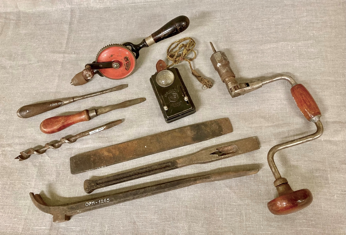 Lommelykt med ekstra uttak, med en ledning som gir strøm til en liten lyspære montert på et trehåndtak. Festereim i lær med knappehull.