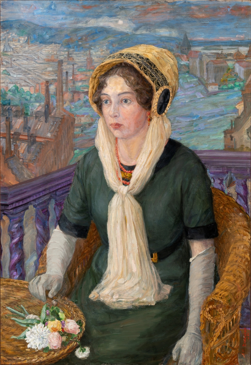 Forfatteren Sigrid Undset sittende i en kurvstol på en altan med utsikt over Kristiania.