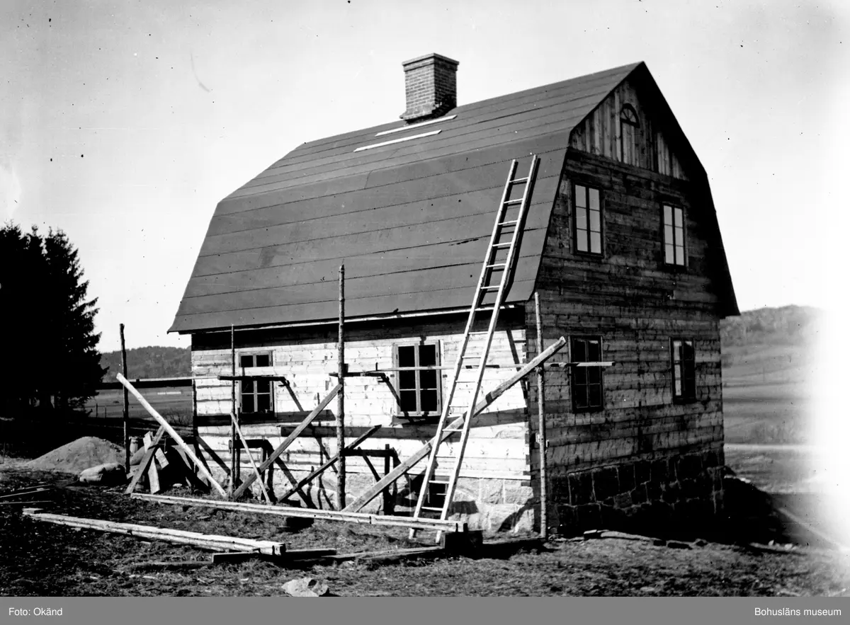 Hus under uppbyggnad eller nedtagning med byggnadsställning runt om och stege upp på taket.