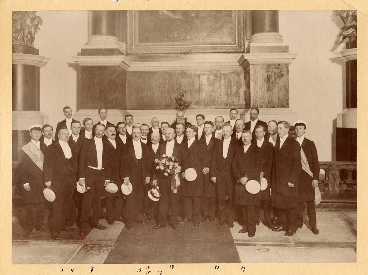 Kalmar Manskör vid altaret i domkyrkan. . På baksidan: 3. Ek ?, 4. Pravitz, 7. Leopold Lundgren, 13. Landsfiskal Johansson, 14. V S Johansson, 15. Målare Carlsson (tenor), 17. Th Berg, 18. "Baspelle" (med skägget).