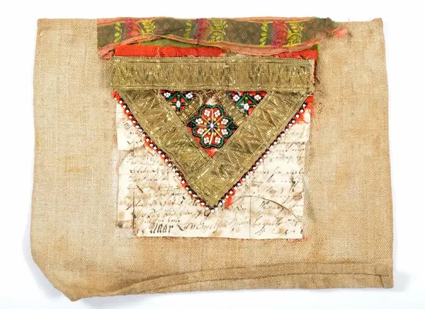 Bringeduk med perler og metallbånd, foret med et brev, som er delvis synlig.