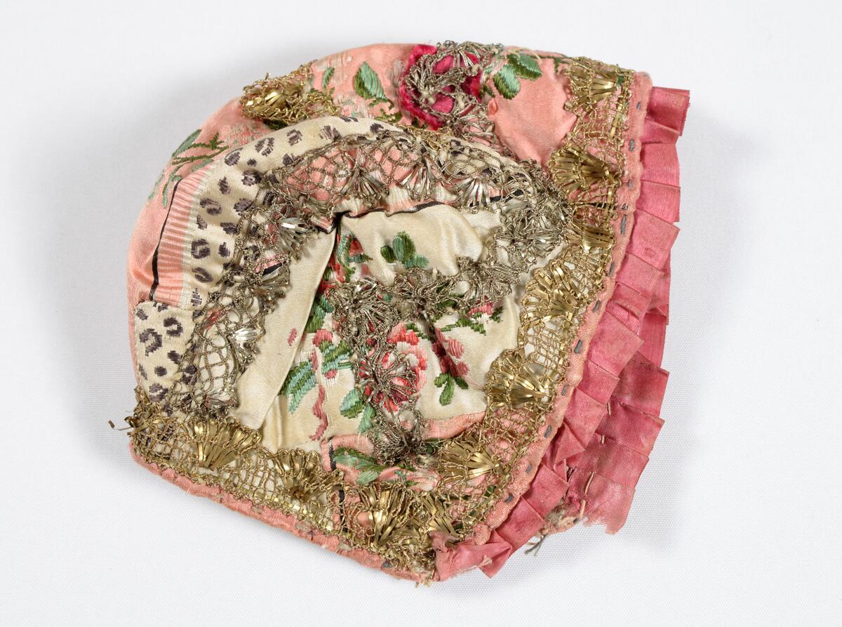 Dåpslue i rosamønstrete silke med sølvkniplinger fra Gudbrandsdalen.