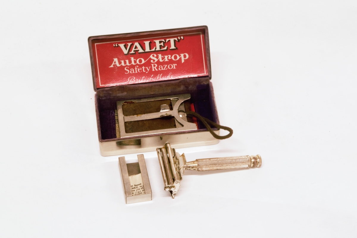 Forniklet metallskrin, med velourfor og hengslet fjærbelastet lokk. Inneholder barbersett bestående av høvel, slipereim og liten metalleske med ekstra barberblad. 
Slipereimen ligger sammenrullet i en holder som er henglset fast i bunnen av skrinet.
Det er bruksanvisninger på norsk og engelsk for barbering og sliping.