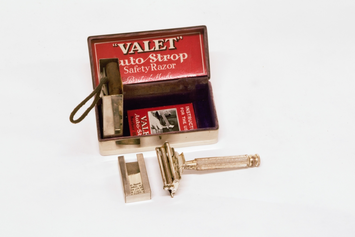 Forniklet metallskrin, med velourfor og hengslet fjærbelastet lokk. Inneholder barbersett bestående av høvel, slipereim og liten metalleske med ekstra barberblad. 
Slipereimen ligger sammenrullet i en holder som er henglset fast i bunnen av skrinet.
Det er bruksanvisninger på norsk og engelsk for barbering og sliping.