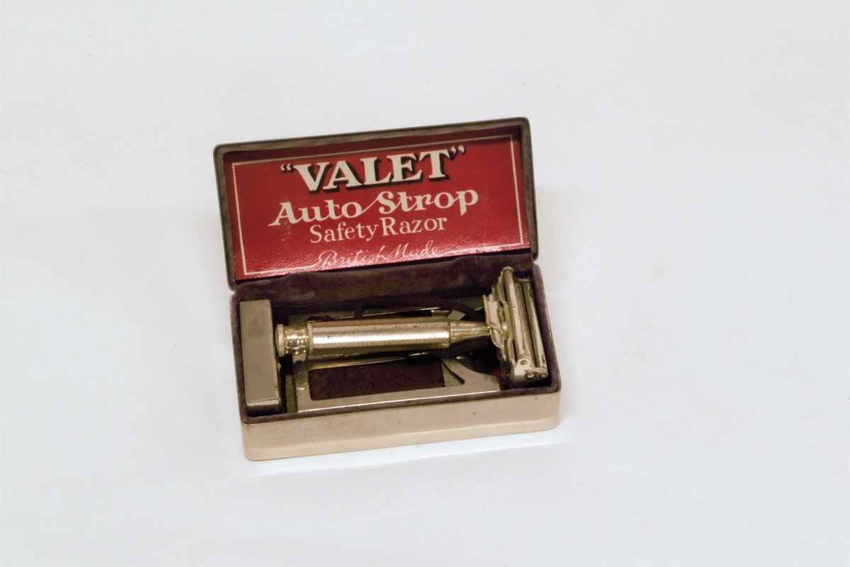 Forniklet metallskrin, med velourfor og hengslet fjærbelastet lokk. Inneholder barbersett bestående av høvel, slipereim og liten metalleske med ekstra barberblad. 
Slipereimen ligger sammenrullet i en holder som er henglset fast i bunnen av skrinet.
Det er bruksanvisninger på norsk og engelsk for barbering og sliping.