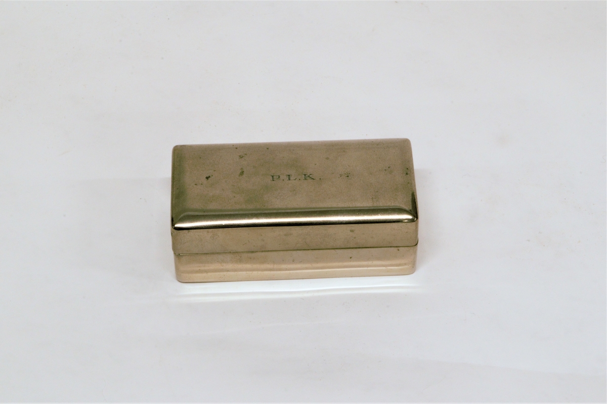 Forniklet metallskrin, med velourfor og hengslet fjærbelastet lokk. Inneholder barbersett bestående av høvel, slipereim og liten metalleske med ekstra barberblad. 
Slipereimen ligger sammenrullet i en holder som er henglset fast i bunnen av skrinet.
Det er bruksanvisninger på norsk og engelsk for barbering og sliping.