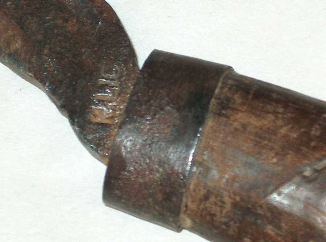 Er av den minste slagen lauvhogg Kjetil arbeide, men typisk i form er både skaftet og sjølve hogget.
Stempla nederst mot tangen som gjeng inn i skaftet. Tangen er gjenomgåande og krøkt i bakkant.
Skaftet er rilla, Kjetil tok å rissa ein spiral oppover heile skaftet, for å så la det ligge i kupa å trekkje vaten, der som det var rissa ville trekkje meire, etter å ha trekt ei stund tok han og helt lauvhogget over varmen og snudde det rund i eldenden. Etter ei tid var treverket millom rissinga forkola og kunne "bystast" vekk, og rissinga stend at som relieff i treverket. Skaftet har  ein 1,5 cm brei holk.
Sonen  Nils K .L nytta seg og av den same teknikken.
Det er soneson som opplyser dette, Kjetil N Lio, (født 26/12- 1930)