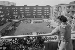 Tensta. En kvinna står på en balkong och blickar ut över en 