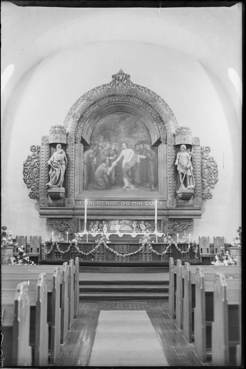 Altertavlen i Rjukan kirke før ombyggingen. Alteret er pyntet med levende lys, kalk og skål for nattverd. Det er hengt opp blomsterranker rundt alterringen og dekorert med blomsteroppsatser i koret.