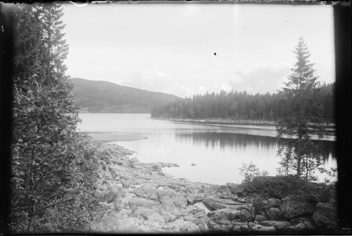 Utløpet av elven Gjøyst ved Sandven. Tinnsjøen og utsikt mot fjell ved Tinn Austbygd på andre siden av vannet.