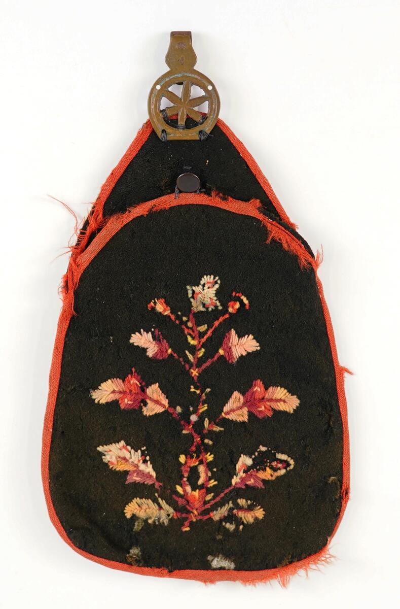 Blomeranke brodert på, sekstakka stjerne eller blome i massingkrok.