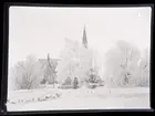 Snötäckt landskap med kyrka i bakgrunden.